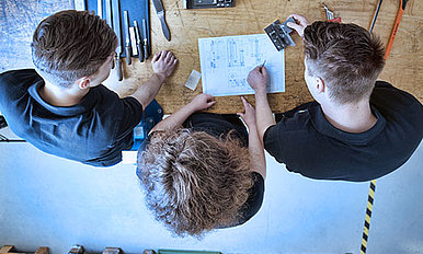 Three interns at a workbench